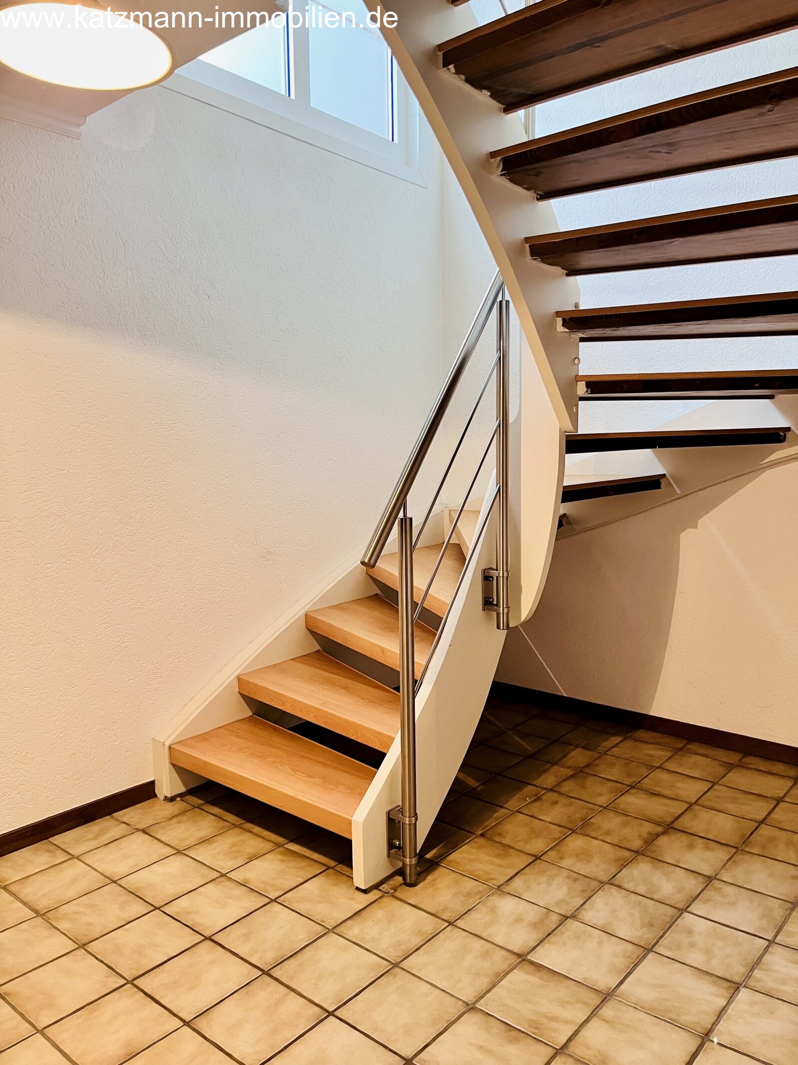Escalier design baigné de lumière avec une élégante structure de rampe en acier inoxydable - Connexion moderne entre les étages avec une finition en bois de haute qualité