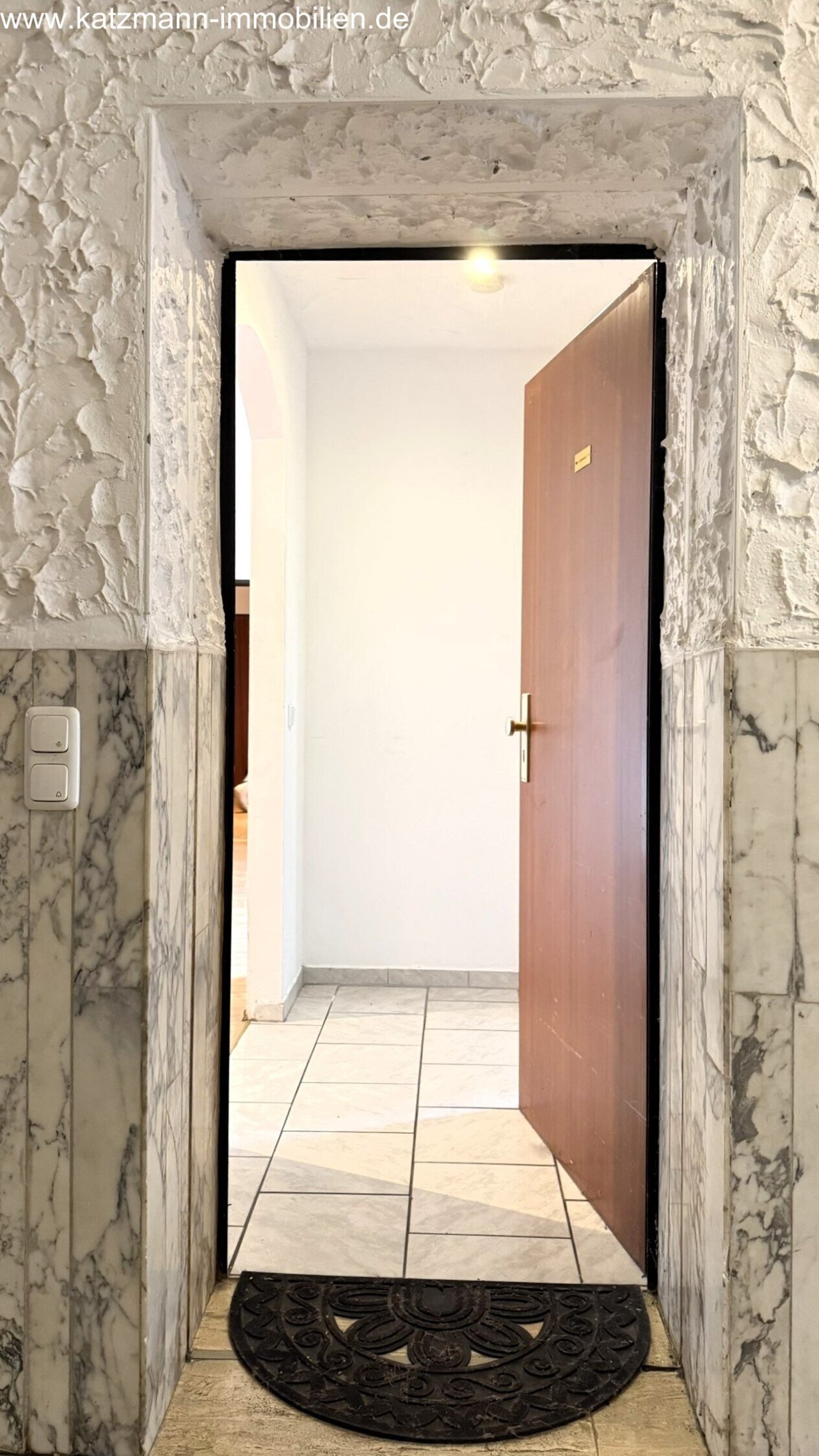 Ingresso esclusivo: cornici in marmo di pregio e porta d'ingresso disegnata invitano a benvenuto!