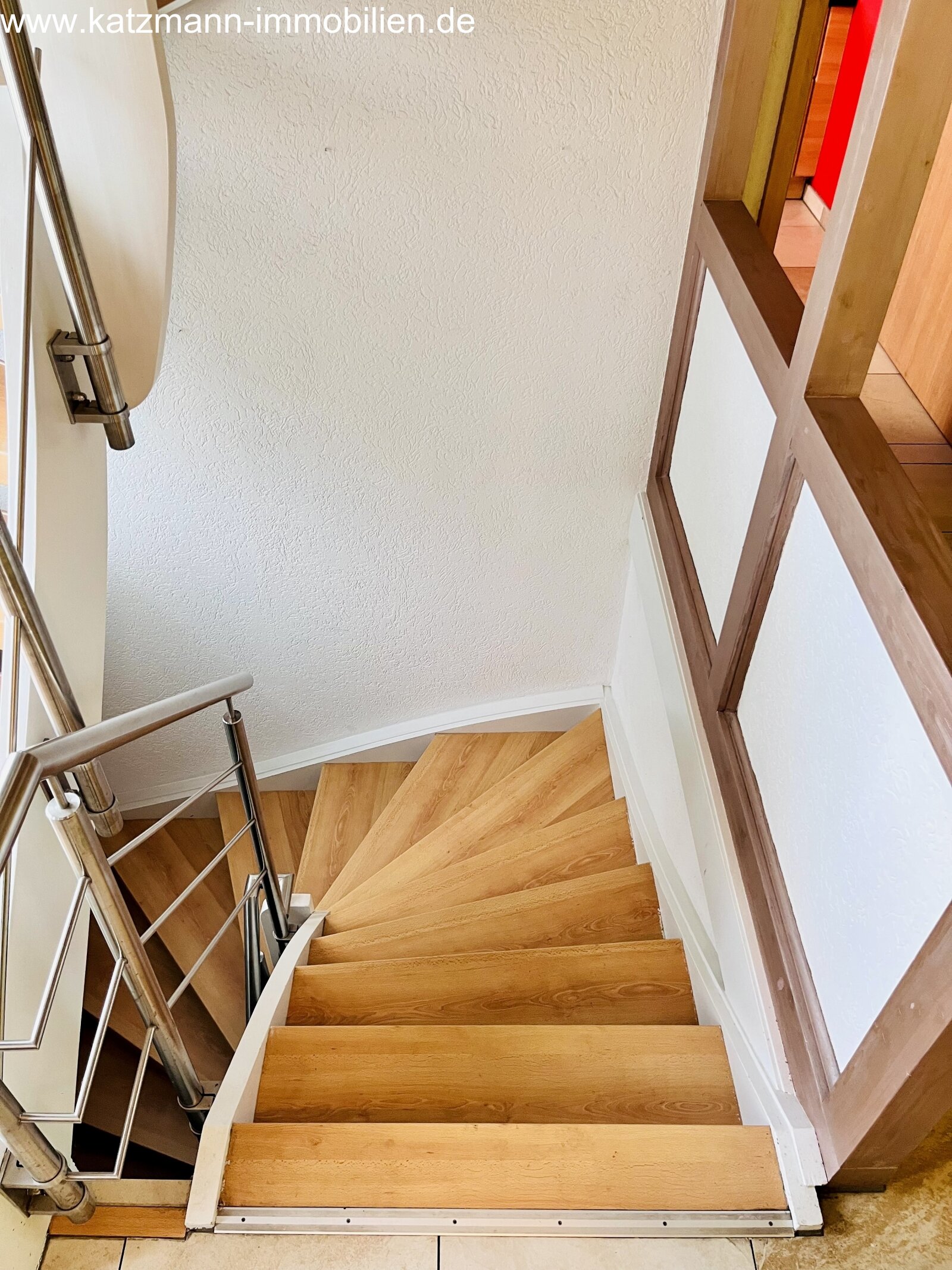 Scala a design con elegante curva: gradini in legno di alta qualità e ringhiera moderna in acciaio inossidabile collegano i piani con stile